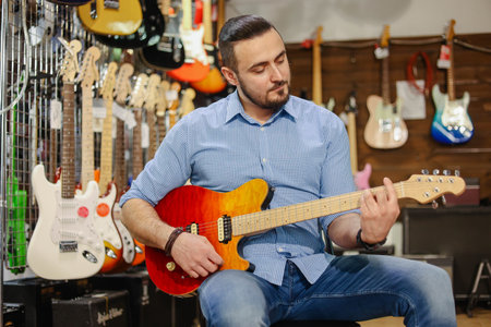 Male musician or customer with beard playing electric guitar at music storeの写真素材