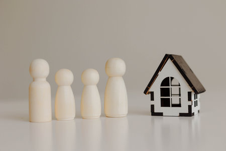 Real estate concept. Wooden people figure standing with mini wooden houseの写真素材