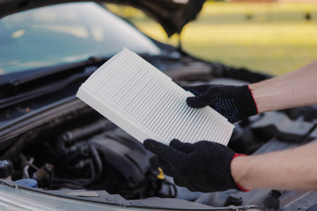 Auto mechanic holds a new car cabin air filter to replace the old filter.の写真素材