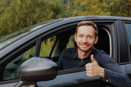 Happy man driver showing thumbs up and smiling at camera in car.の写真素材
