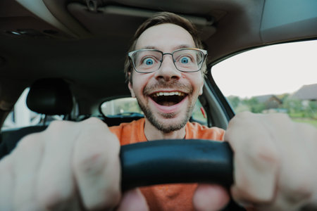 Funny happy driver in glasses is staring at the road and holding the steering wheel. Novice driver learning to drive.の写真素材