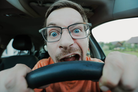 Angry driver in glasses bites the steering wheel.の写真素材