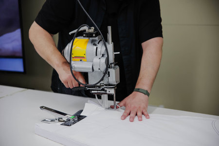A man makes clothing patterns with a cutter knife in a factory. Cutting room.の写真素材