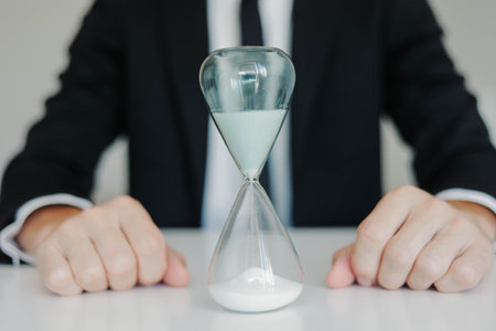 Young businessman with hourglass. Concept of time management and deadline.の写真素材