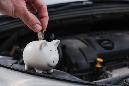 Piggy bank money box on a car with the hood open. Insurance or motoring cost concept.の写真素材