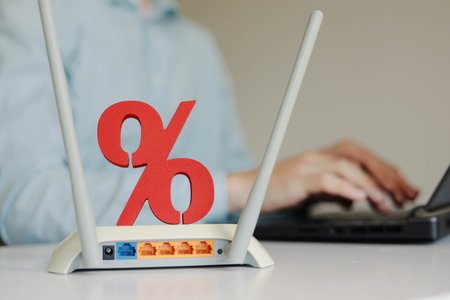 Wireless high speed wifi router with sign of percent on the table. Man using laptop on the backgroundの写真素材
