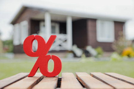 Wooden house on the background of a red percentage sign, representing mortgage rates, real estate investment, and insurance.の写真素材