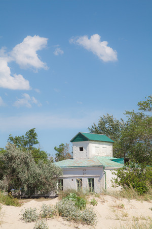 Old building with a green roof on a sea beach on a background of blue sky and trees sunny summer dayの写真素材