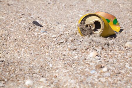 Crumpled tin cans of drink on a clean beach thrown as garbageの写真素材