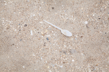 Disposable plastic spoon thrown on the clean sea beach as garbageの写真素材