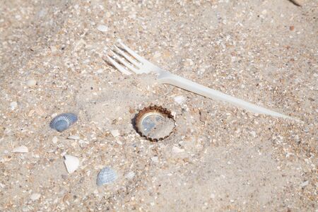 Plastic forks and rusty beer cap on a clean beachの写真素材