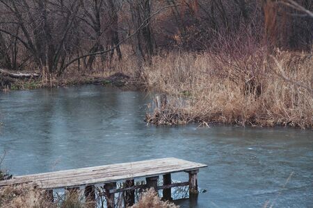 Old wooden platform on frozen pond in early spring dayの写真素材