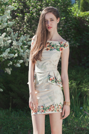 Beautiful young girl model posing near white blooming lilacs at sunny spring dayの写真素材
