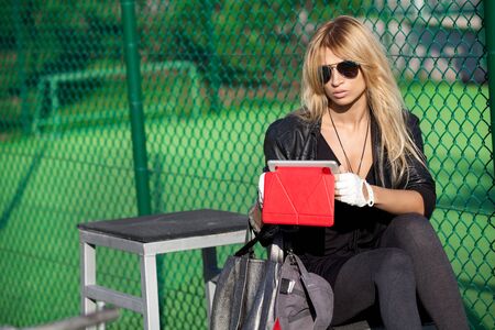 Glamorous blonde with tablet on playground at sunny afternoonの写真素材