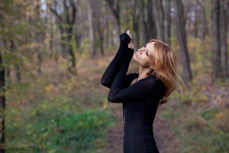 Pretty mysterious woman in black dress posing in the forestの写真素材
