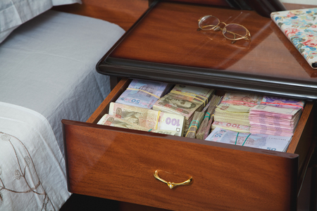 Bundles of banknotes in bedside table filled with Ukrainian cashの写真素材