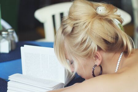 Beautiful blonde fell asleep over a bookの写真素材