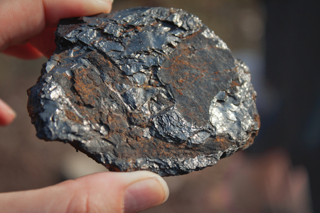 Piece of coal in hand glitters in the sun