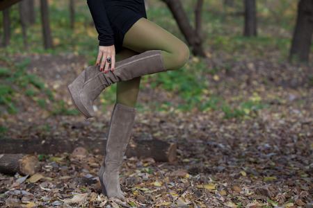 Girl in green stockings in autumn forest gracefully bent leg in suede bootsの写真素材