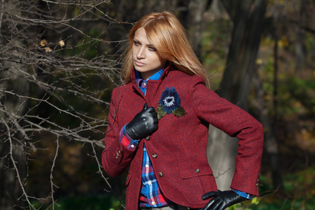 Pretty woman with flowing hair in tweed jacket and leather gloves walking and posing in autumn forestの写真素材