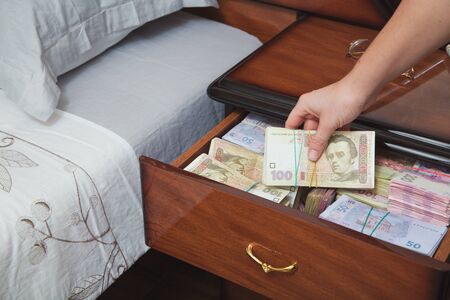 Hand pulls out wad of money from the bedside table filled with Ukrainian cashの写真素材