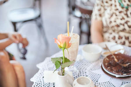 Fresh rose in white vase on table at outdoor cafeの写真素材