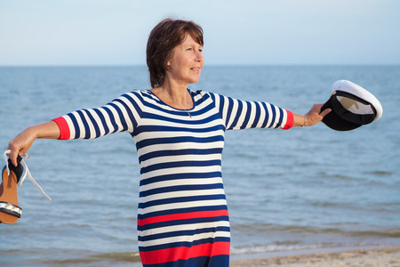 Elderly pretty woman happily raised his hands to the sun on the beachの写真素材