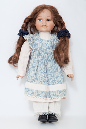 Vintage porcelain doll girl with long braids brown hair on a white backgroundの写真素材