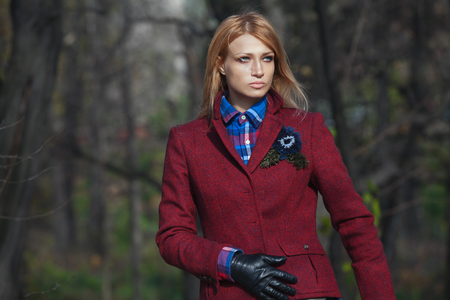 Pretty woman with flowing hair in tweed jacket and leather gloves walking in autumn forestの写真素材