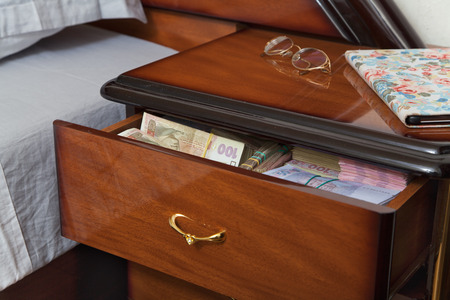Bundles of banknotes in bedside table filled with Ukrainian cashの写真素材