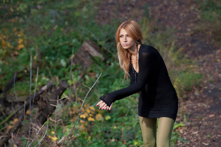Attractive mysterious woman in a slinky dress posing in an autumn forestの写真素材