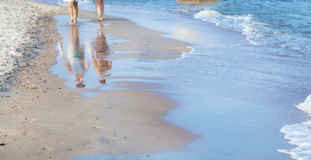 Female feet on the sea beach in wave at summer sunny dayの写真素材