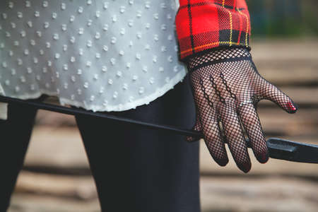 Horsewoman hand in fishnet glove holding a stack for riding in forest at sunny dayの写真素材