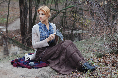 Portrait of beautiful girl knitting in vintage style on nature backgroundの写真素材