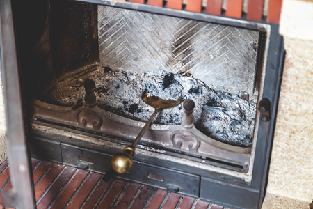 Brass blade with a long handle lies in a heap of ashes in the furnace fire extinguishedの写真素材