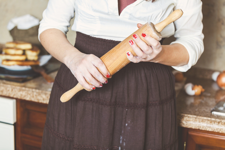 Woman in brown skirt wooden rolling pin with two handsの写真素材