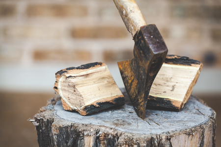 Hatchet sticking in a stump near halves are split logs closeup