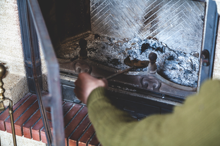 Hand picking up a man ash out of the fireplace on a brass blade with a long handleの写真素材