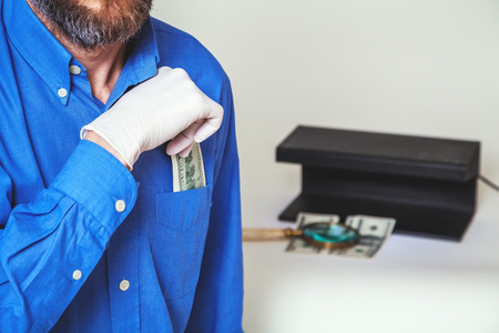 man with a beard in a blue shirt pulls from his breast pocket a dollar billの写真素材