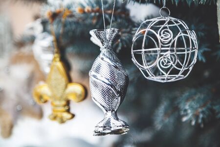 Group of Christmas toys of silver and yellow weigh on green branches snow-covered Christmas tree closeup
の写真素材