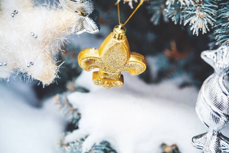 Group of Christmas toys of silver and yellow weigh on green branches snow-covered Christmas tree closeup
の写真素材
