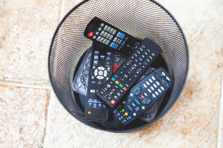 several panels of different forms of remote control are dumped into the waste-paper basket closeup
の写真素材