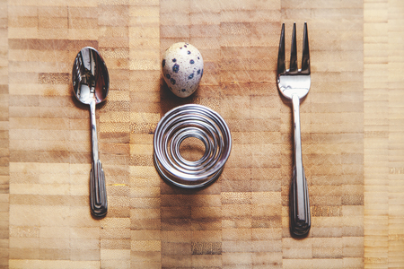 Egg quail, spiral stand, fork, spoon lie on the board. Set for dietary breakfastの写真素材