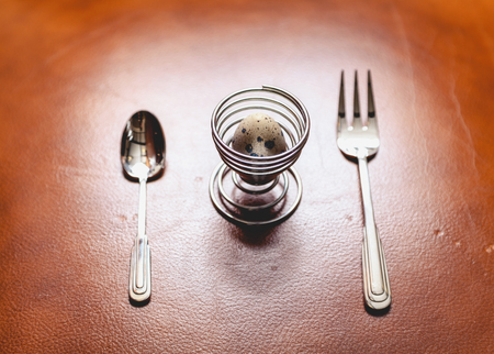 quail egg is inside the spiral stand on the skin. Nearby lay a spoon and fork
