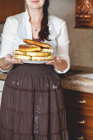woman in a skirt holding a plate with a big mouth-watering fried piesの写真素材