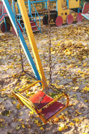 Empty children's swing in the garden on the court circuits in autumn park with sand closeupの写真素材