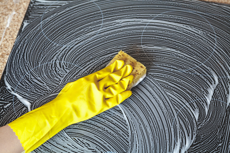 Electric plate washing. Hand in a yellow rubber glove. Rubs the hob of a modern cooker with a foam sponge
の写真素材