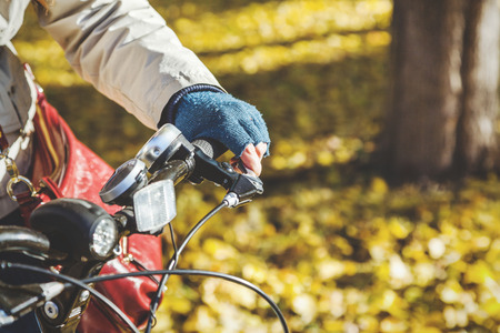 Female hand with beautiful manicure in a blue woolen mittens
presses the brake lever on the handlebars autumn day close-up
の写真素材