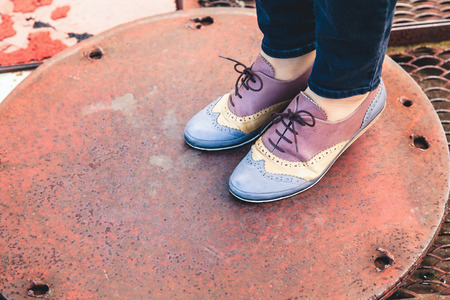Female feet in stylish shoes brogues lifted on the fingers in a circular metal coverの写真素材