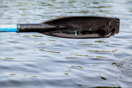 Black plastic paddle the oars above the water after the stroke close up. Drops of water flow downの写真素材